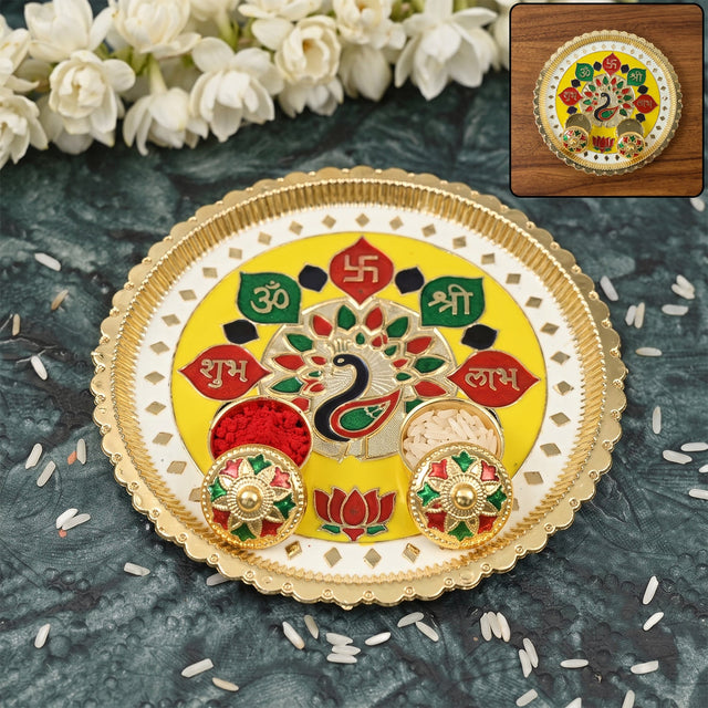 A golden and yellow pooja thali with a peacock design, two small bowls, and scattered rice grains.