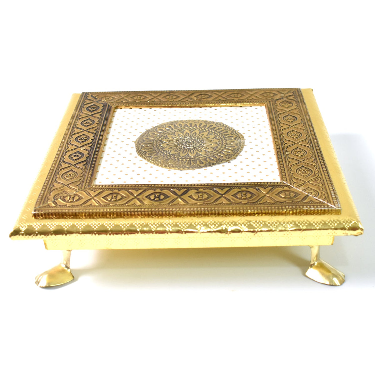A side view of a golden square pooja chowki with a white and gold mandala design on its surface.