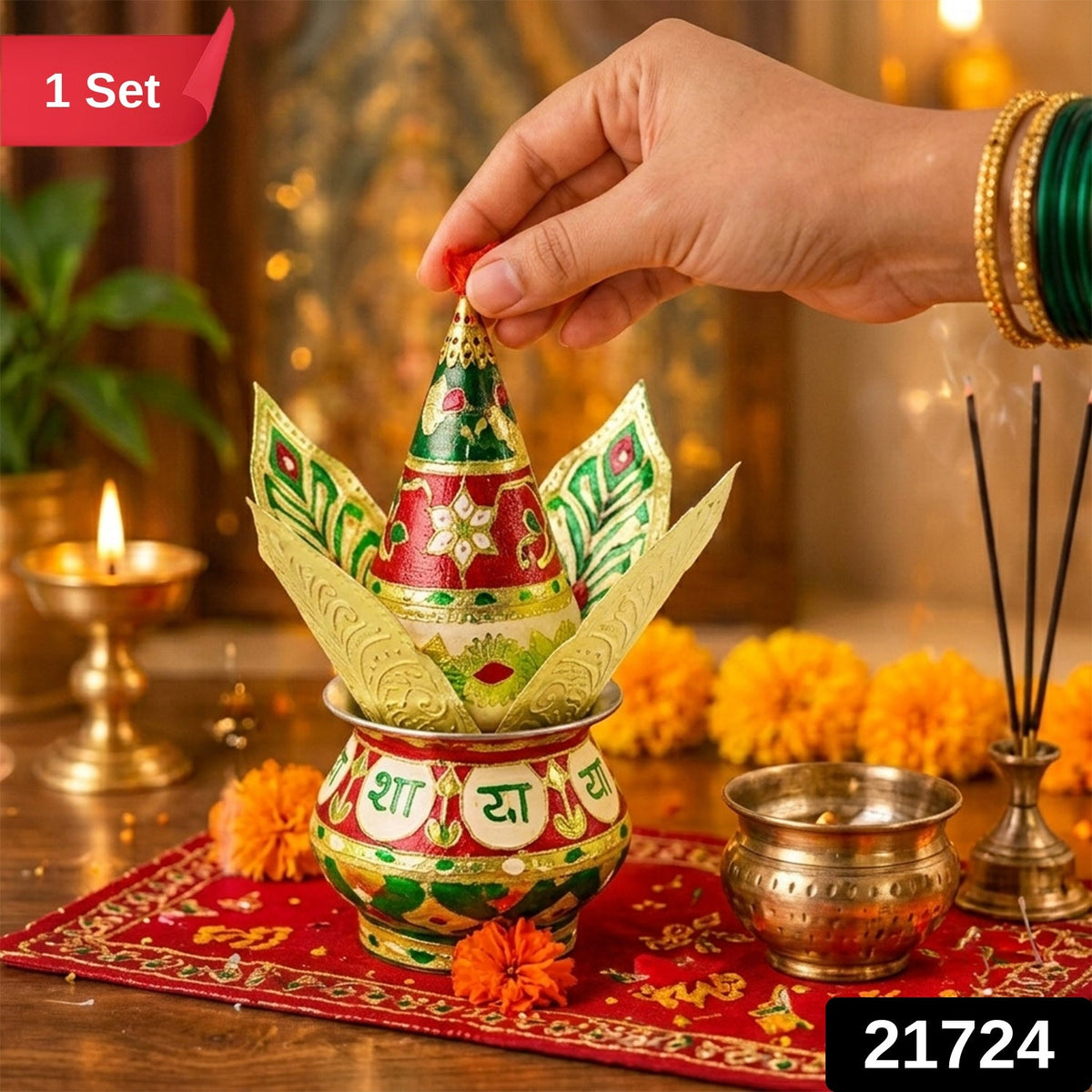 A hand places a red tassel on a decorative kalash with golden leaves, with incense and a small brass pot nearby.